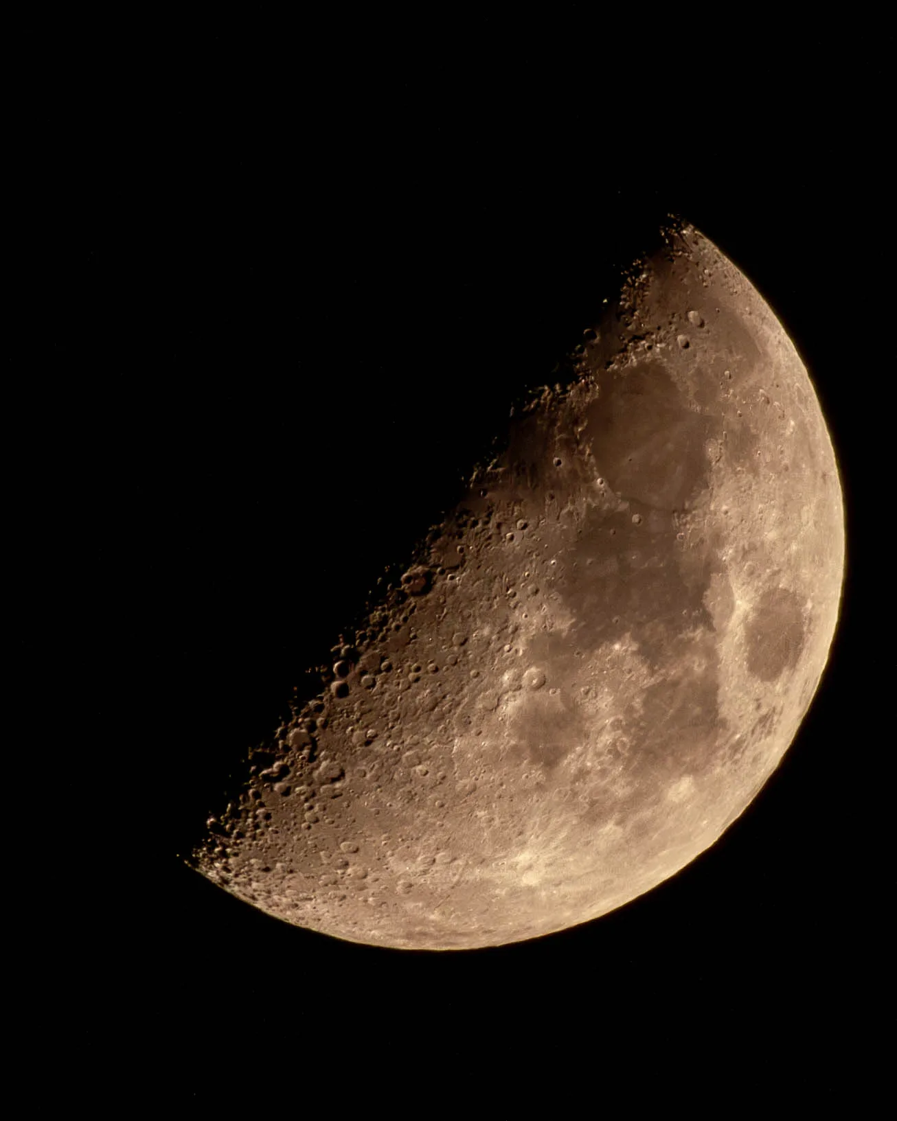 Close-up of a half moon with crater detail on a black sky